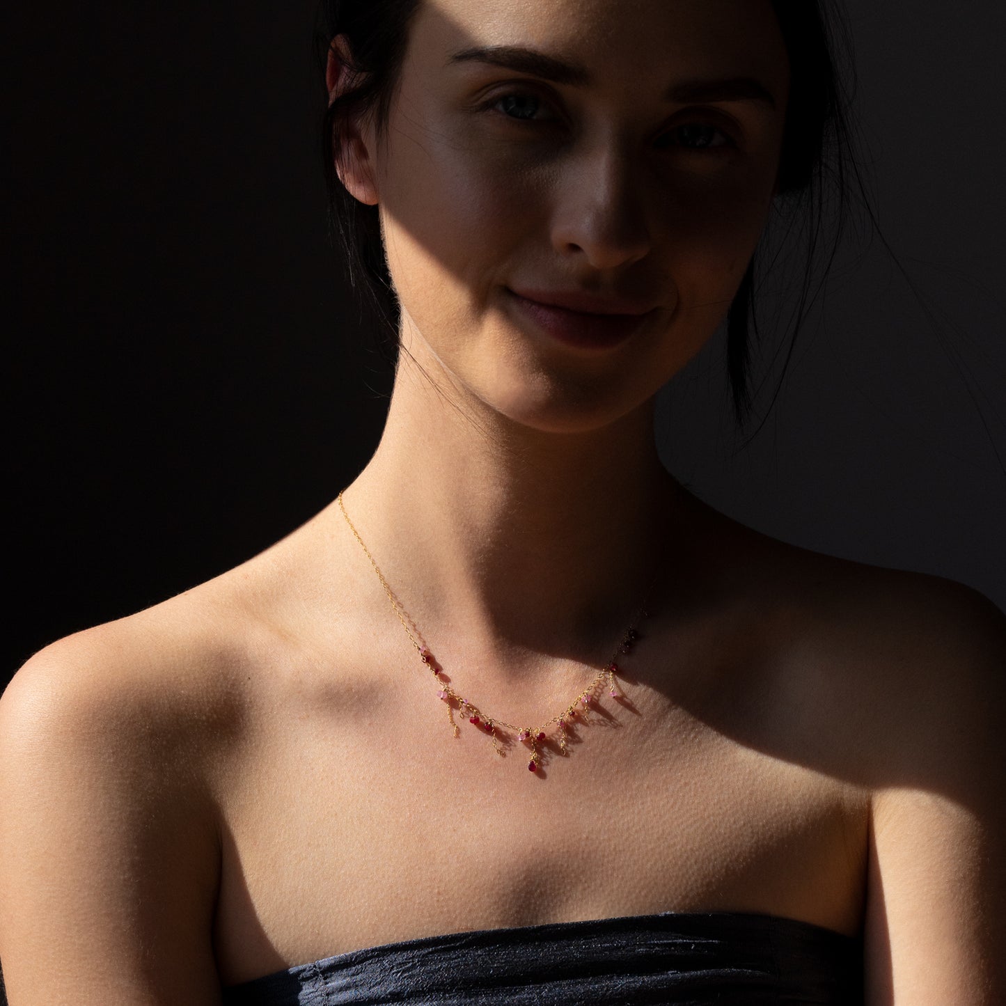 18ct yellow gold chain necklace with various tones of Ruby beads and hanging chains on model
