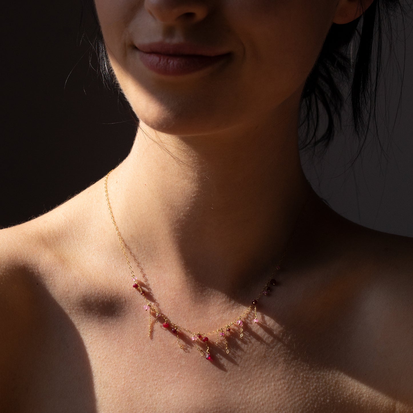 18ct yellow gold chain necklace with various tones of Ruby beads and hanging chains on model