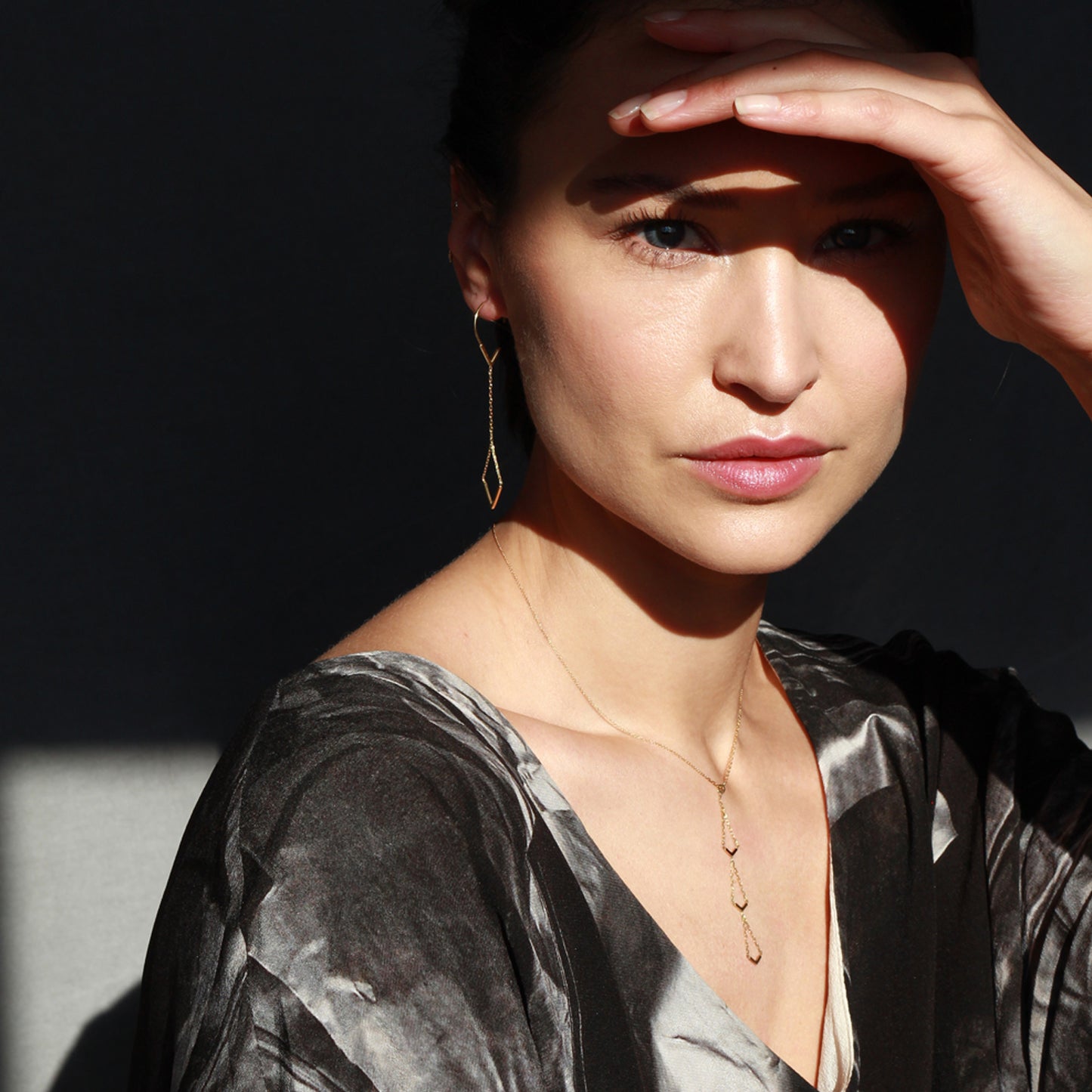 18ct yellow gold hook earrings with V-shaped drops and 18ct gold necklace with triple V drop on model