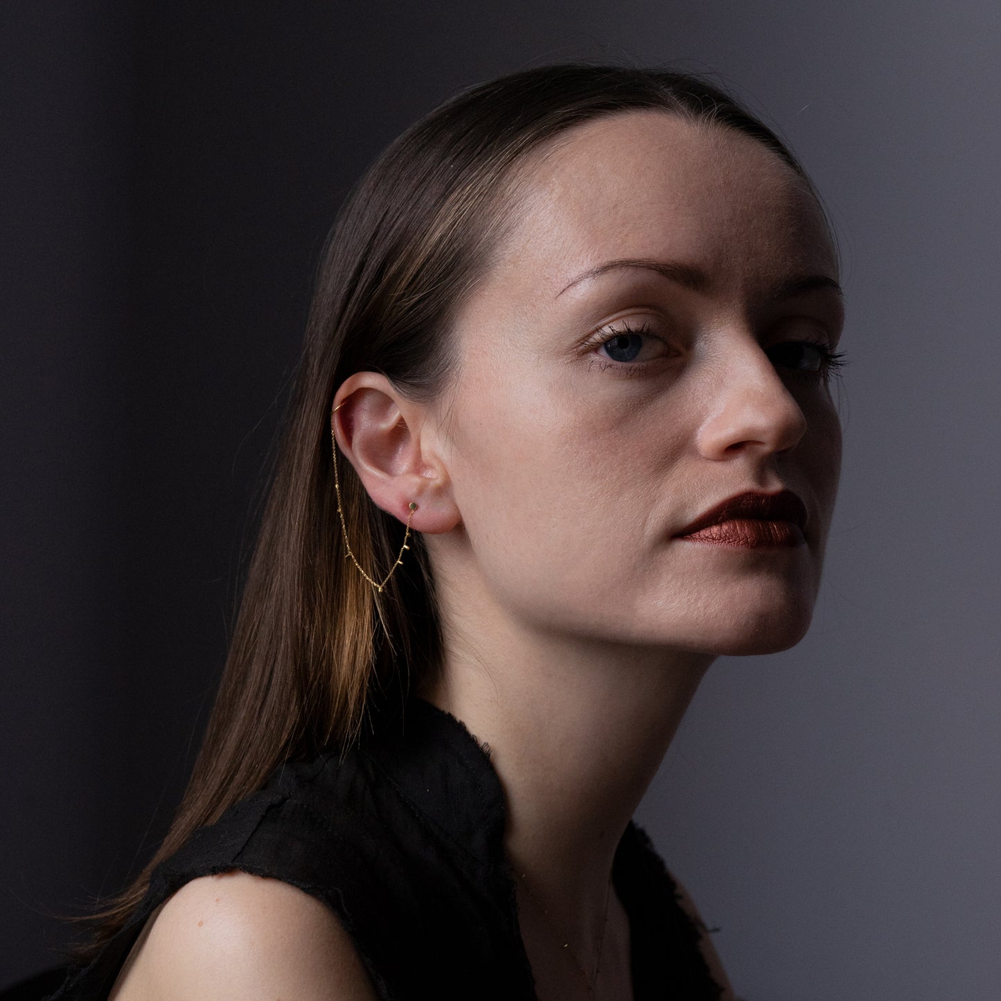 This modern 18ct yellow gold stud to cuff earring is connected by fine chain sprinkled with a shimmering of gold embellishments. on model