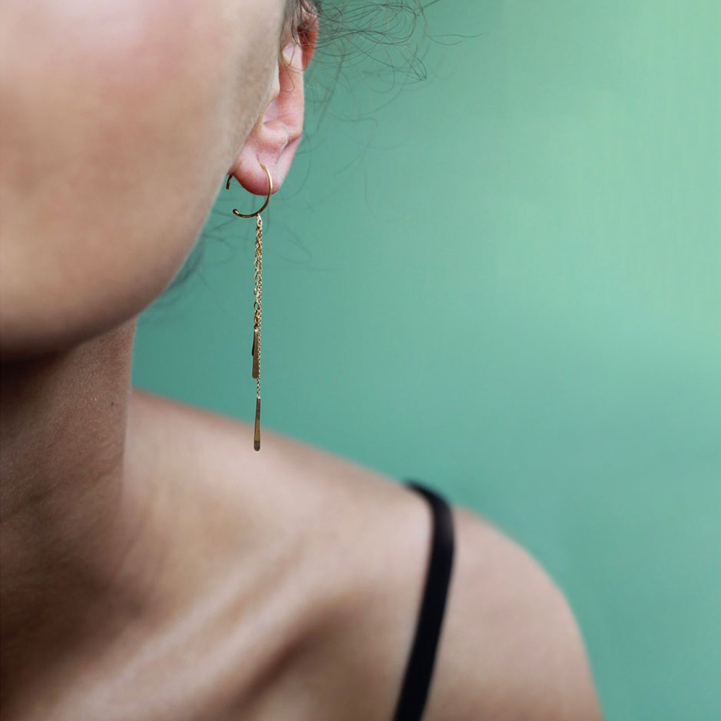 These 18ct yellow gold small hoop earrings are part of our Sycamore collection. They have 3 strands of hanging chain with handmade and flattened gold bar drops. on model