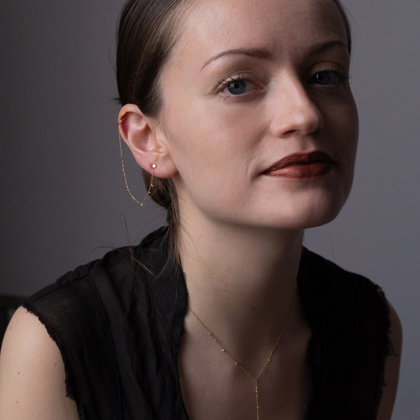 This modern 18ct yellow gold stud to cuff earring is connected by fine chain sprinkled with a shimmering of gold embellishments. on model