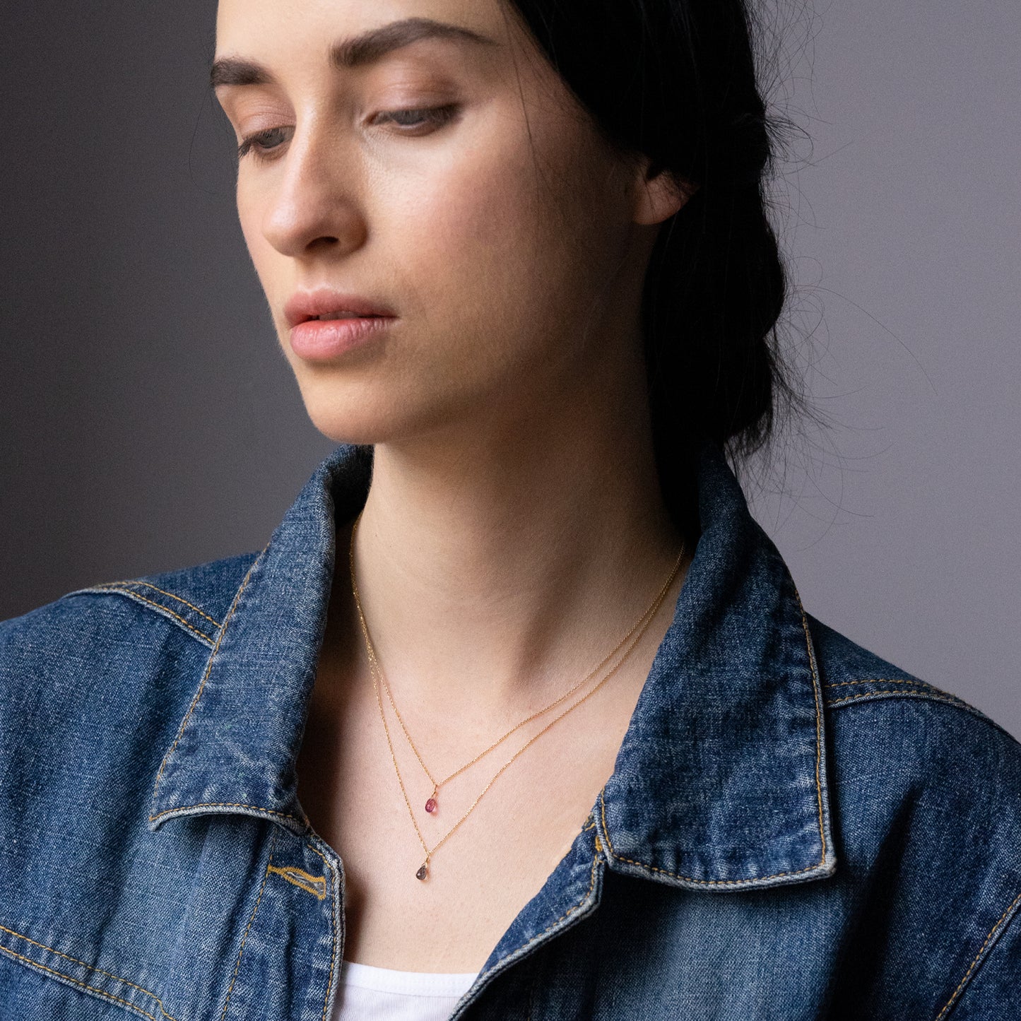 Sweet Pea 18ct yellow gold chain with pink sapphire briolette drop pendant layered with a green sapphire briolette drop necklace on model. 20% of sale going to Breast Cancer Support