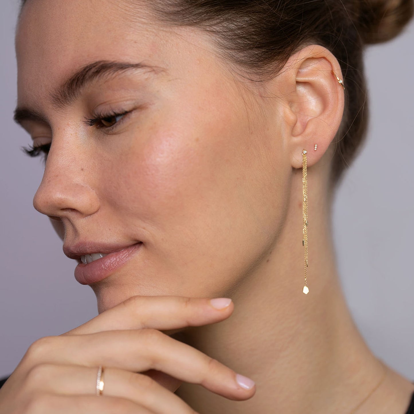 18ct Gold diamond stud with three hanging chains and mixed gold shapes on ends on model