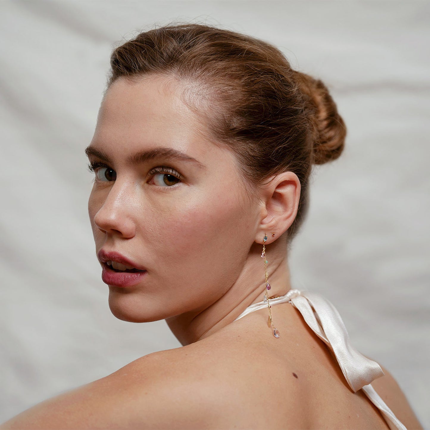 18ct Gold claw set swiss Blue Topaz marquise stud earrings with a dangling long chain with mixed stones and gold leaves worn by model