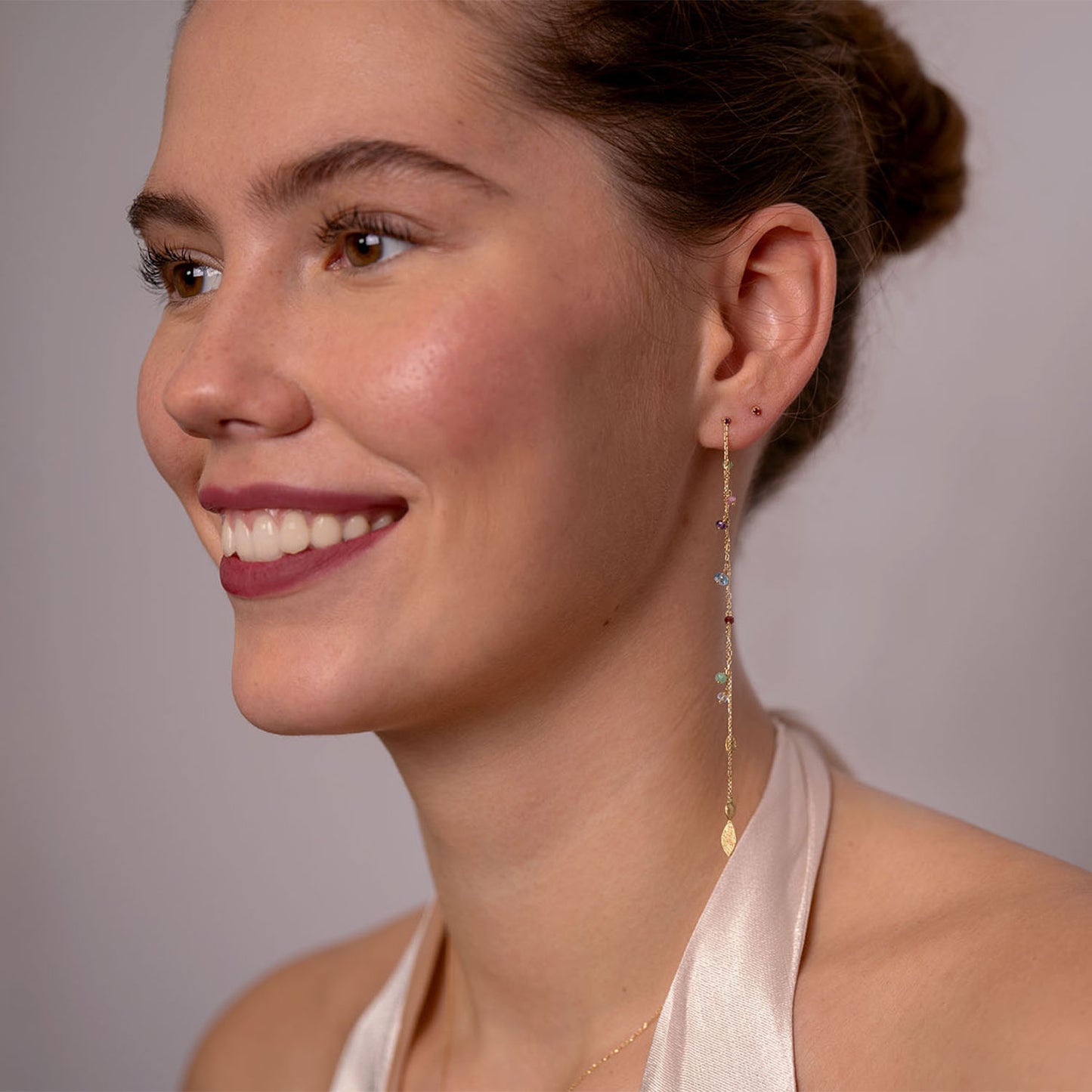 18ct Gold claw set Pink Sapphire stud earrings with a dangling long chain featuring mixed stones and gold leaves worn by model