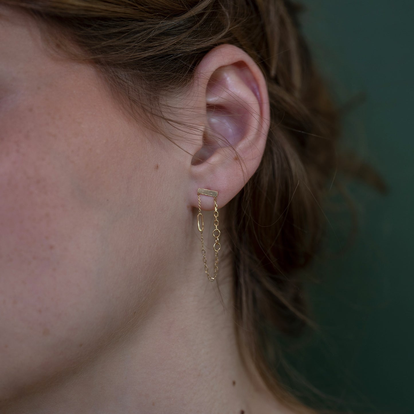 18ct Gold Chains Galore looped around dangling stud earrings on model