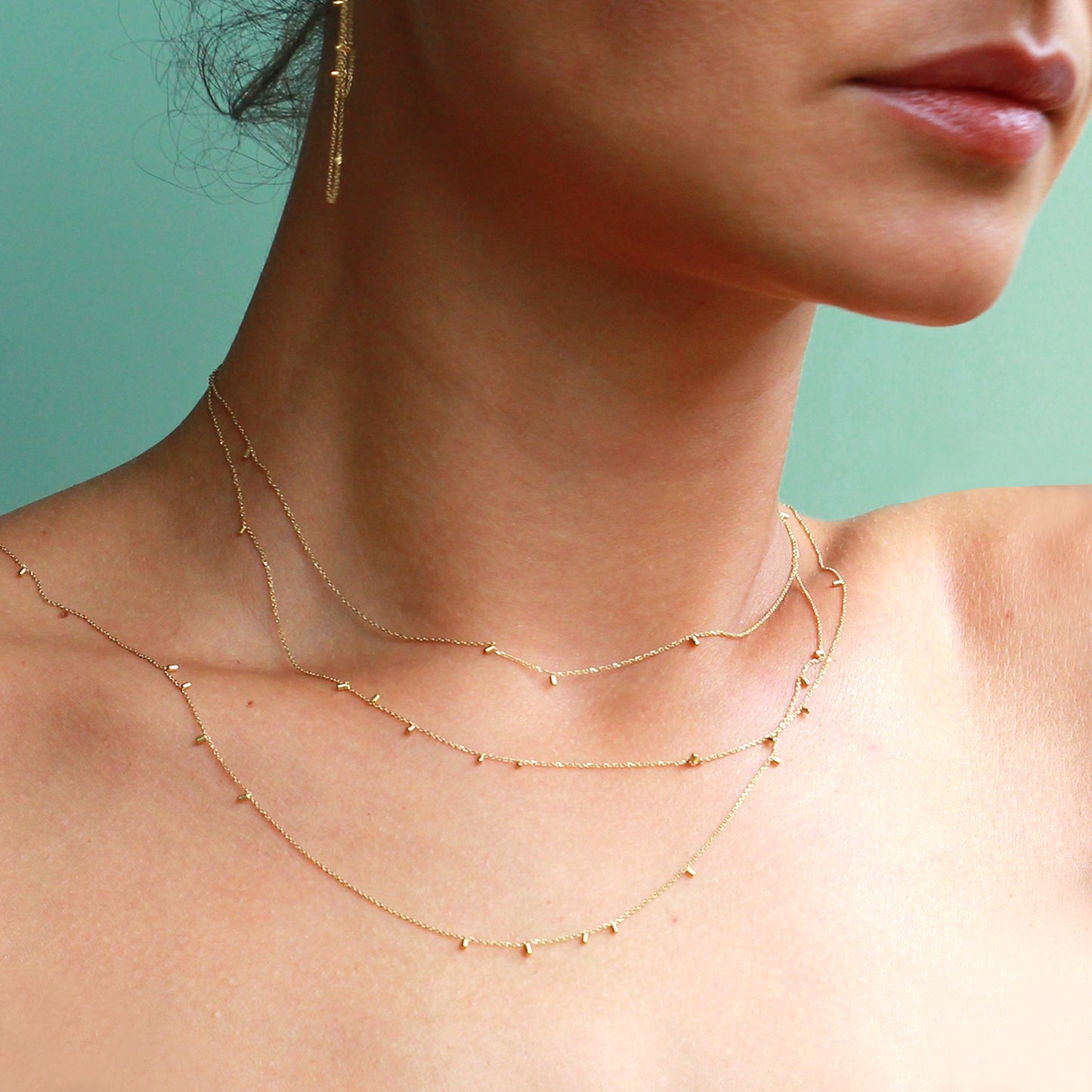 This fabulous long 18ct yellow necklace made of fine chain sprinkled with a shimmering of gold embellishments is part of our Gold Dust Collection on model