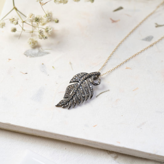 This 9ct yellow gold fine chain necklace features an oxidised silver feather set with grey brilliant cut diamonds.