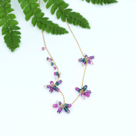 18ct yellow gold chain necklace with beaded clusters of London blue topaz, amethyst, pink Amethyst and hot pink sapphire, from our Roses & Violets collection lying flat.