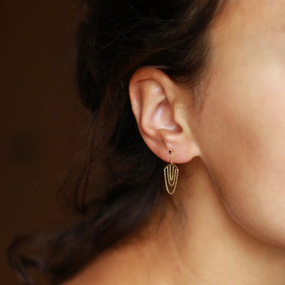 Sweet Pea 18ct yellow gold Nouveau Now black diamond stud earrings with hanging gold arcs with layered chain on model. 