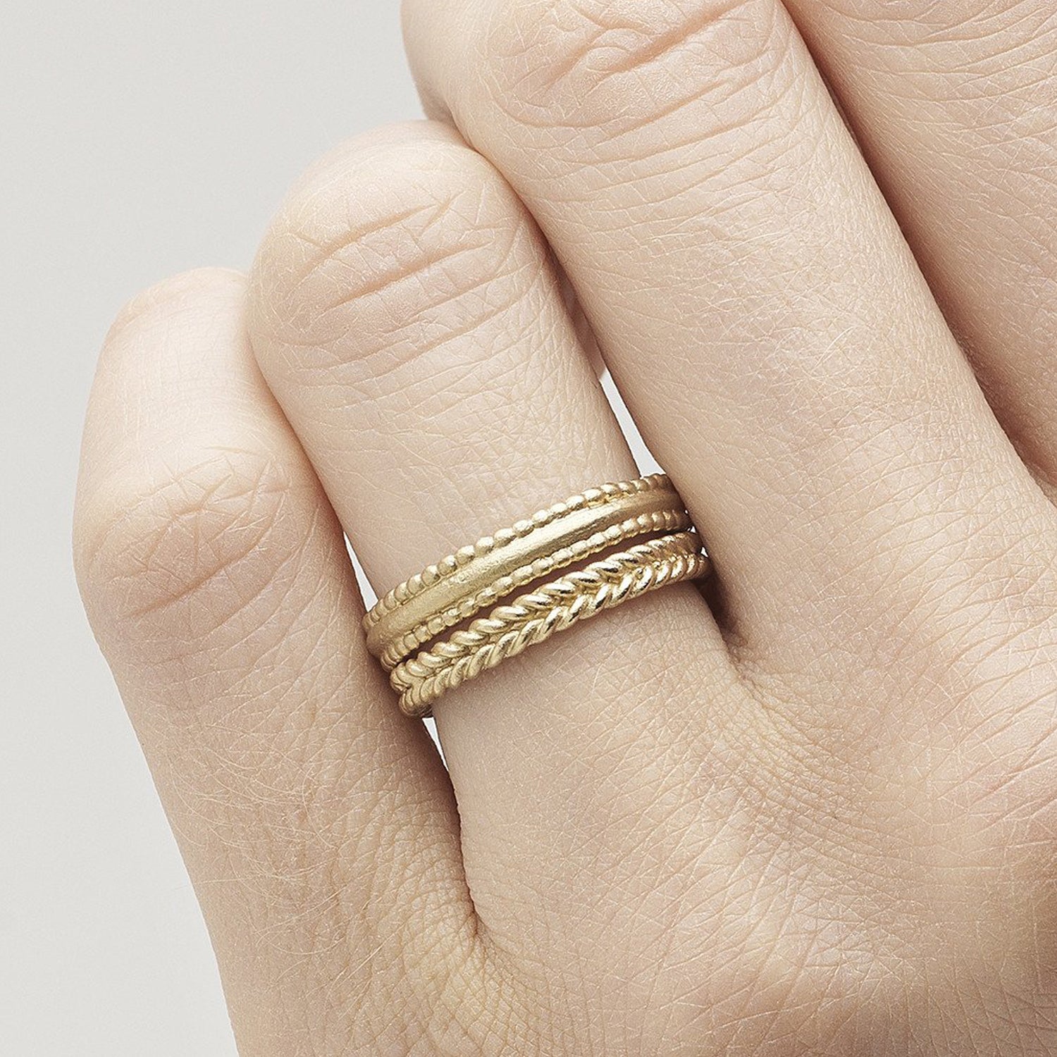 14ct brushed yellow gold Ruth Tomlinson beaded edge band ring stacked with plaited band ring. Alternative wedding band ring.
