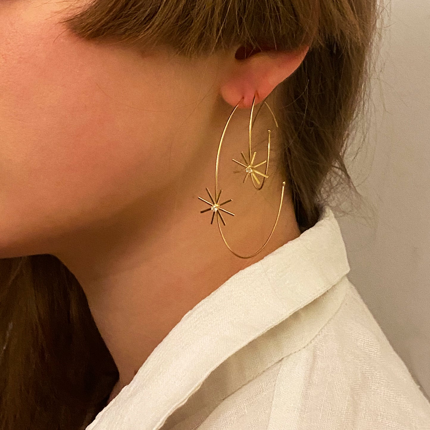 These 18ct yellow gold fine medium diamond hoop earrings are from our Pop Up Daisy Collection. The Flower motif is made up from fine gold petals and features a central Diamond set collet on model