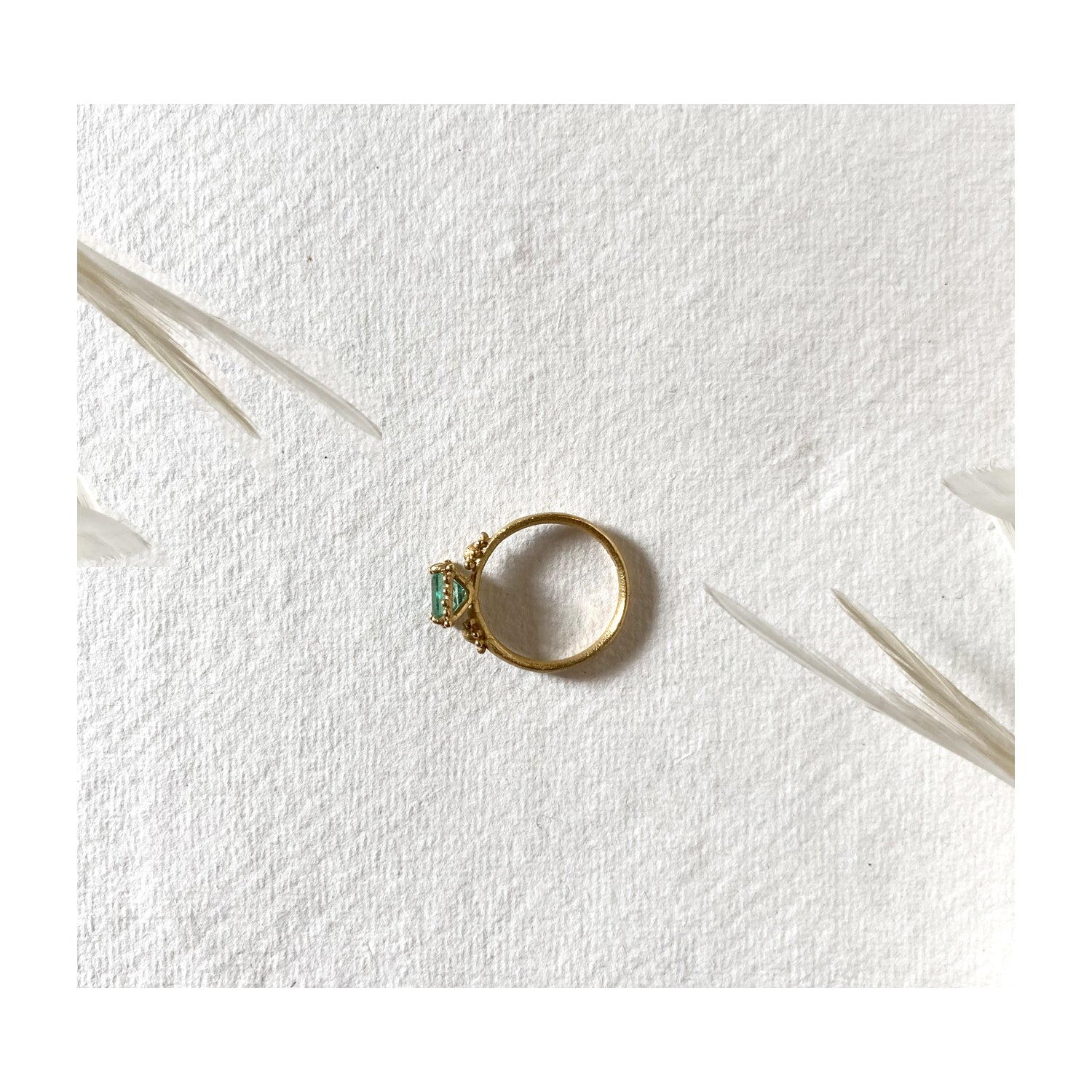 Top view of Ruth Tomlinson 18ct yellow gold ring with square facetted solitaire emerald with beaded granulation surround engagement ring. Alternative engagement ring. Organic emerald ring.  